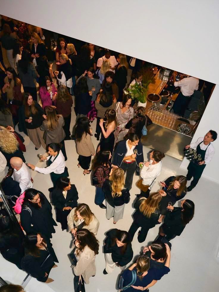 Un vernissage vu d’en haut : une foule en tenue de soirée, un bar au fond.